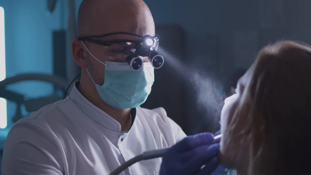 dentist with a headlamp treating a patient in a dark operatory